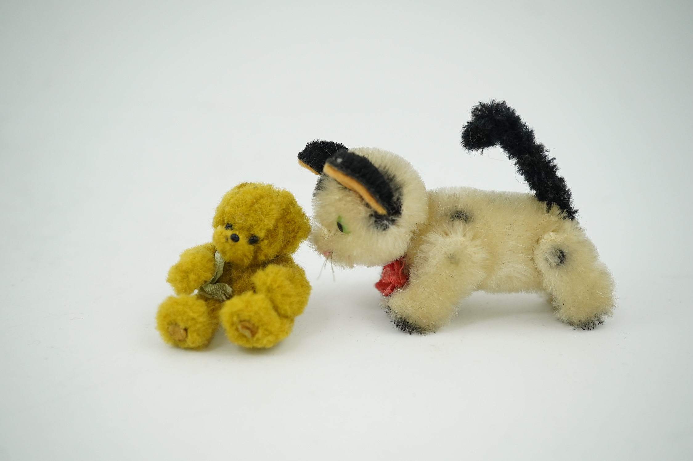 A small Schuco cat with revolving head and a tiny jointed teddy bear, largest 9cm in length. Condition - fair to good